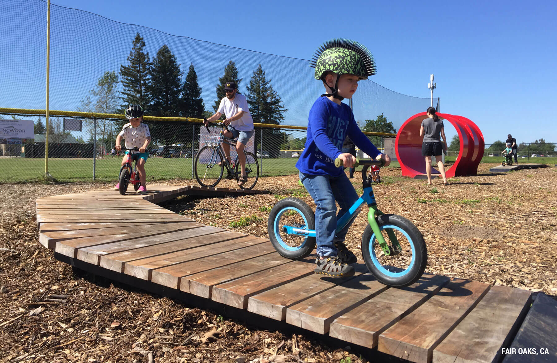 Kids biking on built wood features at a bike playground.